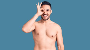 Mayo giyen genç yakışıklı adam el hareketleriyle gülümsüyor ve mutlu yüzüyle parmaklarının arasından bakıyor.. 