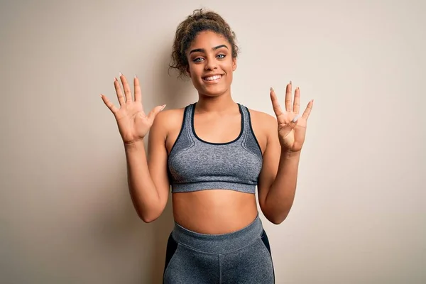 年轻的非洲裔美国女运动员身穿运动服 身穿白色背景的运动服 带着九号手指指尖 面带微笑 自信而快乐 — 图库照片