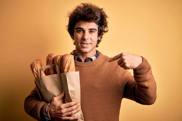 Mladý Pohledný Muž Drží Papírový Sáček Chlebem Stojící Nad Izolovaným — Stock fotografie