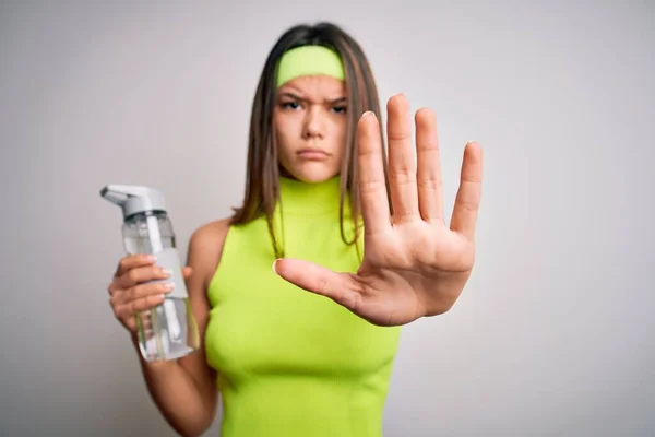 漂亮的女运动员穿着运动服喝着瓶装水提神 用张开的手做停止手势 表情严肃自信 防守姿势 — 图库照片