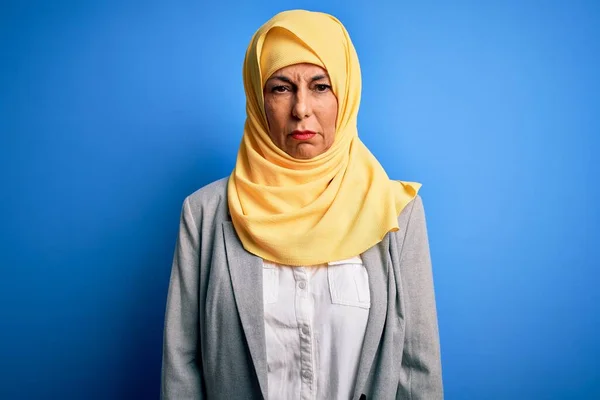 Middle age brunette business woman wearing muslim traditional hijab over blue background depressed and worry for distress, crying angry and afraid. Sad expression.