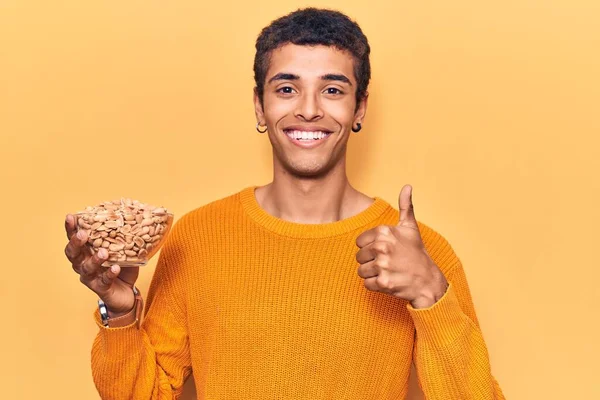 Young African Amercian Man Holding Peanuts Smiling Happy Positive Thumb — Stock Photo, Image