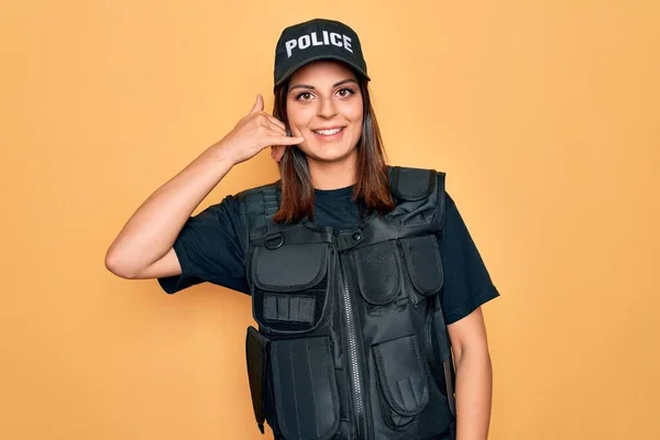 年轻美丽的黑发女警察身穿警服 头戴帽子 面带微笑 手指手画脚地做着电话手势 就像在电话里说话 交流概念 — 图库照片