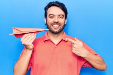 Elinde kağıt uçak tutan genç İspanyol adam mutlu bir şekilde elini ve parmağını gösterdi. 