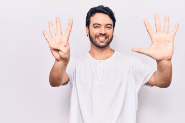 Gündelik kıyafetler giyen genç İspanyol adam dokuz numarayı gösterip işaret ederken kendinden emin ve mutlu bir şekilde gülümsüyor.. 