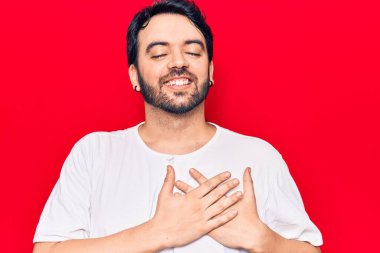 Gündelik kıyafetler giyen genç İspanyol adam elleri göğsünde gülümsüyor, gözleri kapalı ve yüzünde minnet ifadesi var. sağlık kavramı. 