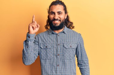 Gündelik giysiler giymiş genç bir Arap başarılı bir fikirle işaret ediyor. Heyecanlı ve mutlu. Bir numara.. 