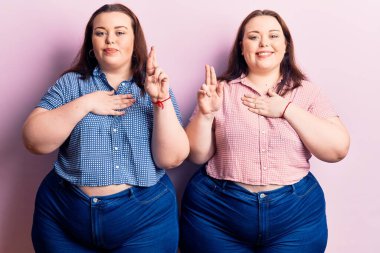 Genç ve cüsseli ikizler gündelik kıyafetler giyip gülümsüyor, elleri göğsünde ve parmakları havada küfür ediyor, sadakat yemini ediyorlar. 