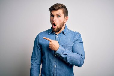 Sakallı, mavi gözlü, sıradan bir kot tişörtü giyen genç, yakışıklı sarışın bir adam..