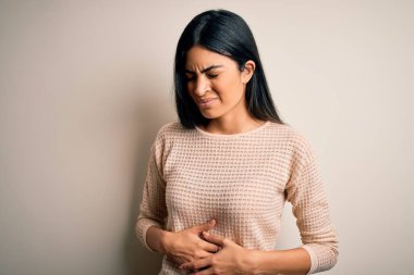 Soyutlanmış arka plan üzerinde zarif pembe süveter giyen genç ve güzel bir İspanyol kadın. Midenin üstünde elle tutuluyor. Çünkü hazımsızlık, acı veren bir hastalık, kendini iyi hissetmiyor. Ache kavramı.