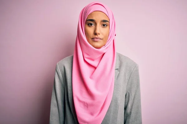 ピンクのイスラム教徒のヒジャーブと顔に深刻な表現とビジネスジャケットを身に着けている若い美しいブルネットの実業家 シンプルで自然なカメラを見て — ストック写真