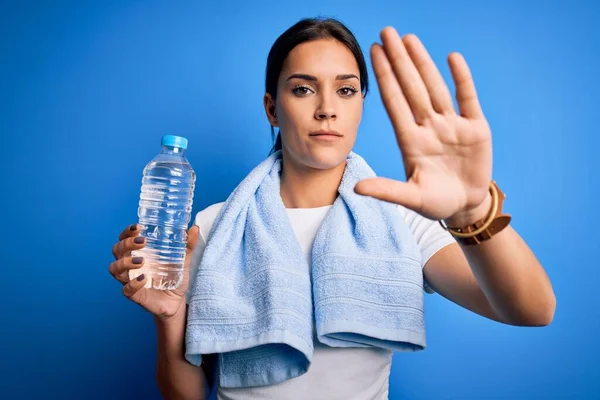 年轻美丽的黑发女运动员 身穿浴巾 喝着一瓶水 张开手 做停止手势 表情严肃自信 防守姿势 — 图库照片