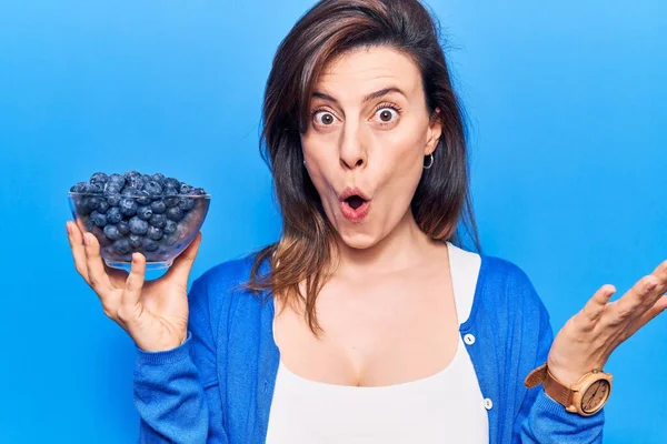 Jovem Mulher Bonita Segurando Blueberries Assustado Espantado Com Boca Aberta — Fotografia de Stock