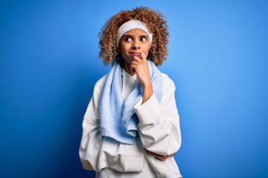 Genç Afrikalı Amerikalı sporcu kadın spor giysisi giyiyor ve elleri çenesinde havluyla soru soruyor, dalgın bir ifade. Düşünceli bir yüzle gülümsüyor. Şüphe kavramı.