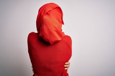 Orta yaşlı esmer kadın izole edilmiş beyaz arka plana geleneksel tesettür takmış mutlu ve pozitif bir şekilde sarılıyor. Sevgi ve özgüven.