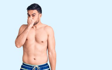 Mayo giyen genç yakışıklı bir adam pis ve iğrenç bir koku alıyor. Nefesini burnunda tutuyor. Kötü kokuyor. 