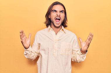İş kıyafetleri giyen genç yakışıklı çılgın ve kızgın bir adam agresif bir ifadeyle bağırıyor ve kollarını kaldırıyor. hüsran kavramı. 