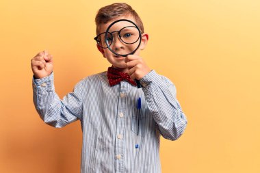 Sevimli sarışın çocuk inek papyonu takıyor ve elinde büyüteçle haykırıyor gururla haykırıyor zaferi ve başarıyı kollarını kaldırarak kutluyor. 