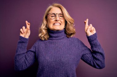 Orta yaşlı, sarışın, sıradan mor balıkçı yaka kazak giyen ve gözlük takan umut ve gözlerin kapalı gülümseyerek el sallayan güzel bir kadın. Şans ve batıl inanç..