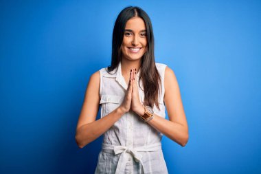 Genç, güzel, esmer bir kadın. Sıradan elbiseler giyip, mavi arka planda dua ediyor. Birlikte dua ediyor..