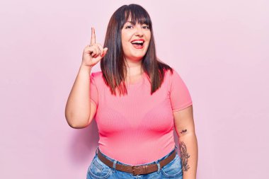 Genç ve cüsseli bir kadın gündelik giysiler giyip başarılı bir fikri işaret ediyor. Heyecanlı ve mutlu. Bir numara.. 