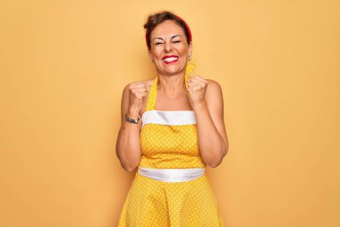 50 'li yaşlarda, sarı arka planda 50' li yaşlarda giyinmiş, başarılı olacağı için heyecanlı kolları havada ve gözleri kapalı zaferi kutlayan bir kadın rozeti takıyor. Kazanan konsept.