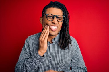 Rastgele gömlek giyen, gözlüklü, dişlerinde diş ağrısı ya da diş ağrısı yüzünden ağızlarına dokunan eli ağrılı genç, Afro-Amerikan bir adam. Dişçi