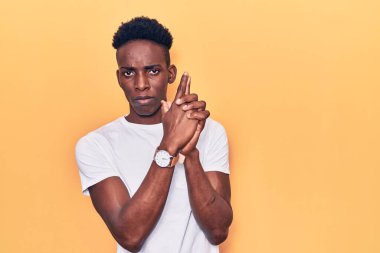 Genç Afro-Amerikan adam gündelik giysiler giyip, el hareketleriyle sembolik silah tutuyor, cinayet silahlarıyla oynuyor, kızgın suratlı. 