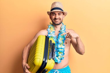 Mayo giyen genç ve kel bir adam ve elinde kamara çantasıyla gülümseyen mutlu bir el ve parmak. 