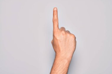 Beyaz arka planda parmaklarını gösteren beyaz tenli bir adamın eli işaret parmağı kullanarak bir numarayı sayıyor. Fikir ve anlayış gösteriyor.