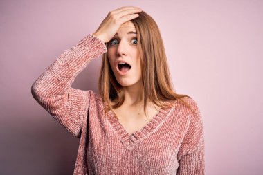 İzole edilmiş pembe arka plan üzerine sıradan süveter giyen genç, güzel, kızıl saçlı bir kadın. Yanlışlıkla el ele tutuşarak şaşırdı, unutma. Unuttum, kötü hafıza konsepti.