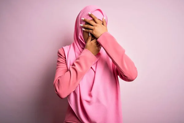 孤立したピンクの背景にイスラム教徒のヒジャーブを身に着けている若いアフリカ系アメリカ人アフリカ人女性手で目と口を覆い 驚きとショックを受けました 感情を隠す — ストック写真