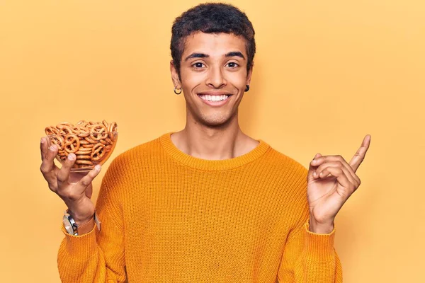 Jonge Afrikaans Amerikaanse Man Met Pretzels Glimlachend Wijzend Met Hand — Stockfoto