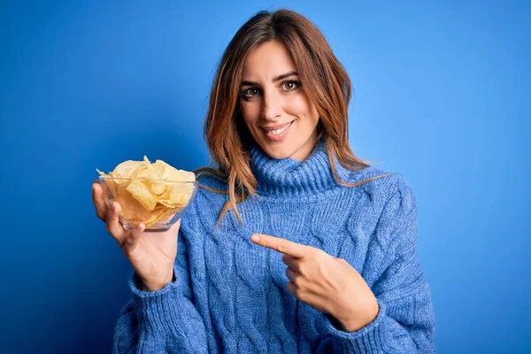Genç Güzel Esmer Kadın Elinde Patates Cipsiyle Mavi Arka Planda — Stok fotoğraf