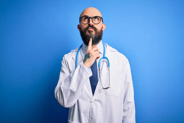 Pohledný Holohlavý Lékař Vousy Brýlích Stetoskopem Nad Modrým Pozadím Přemýšlející — Stock fotografie
