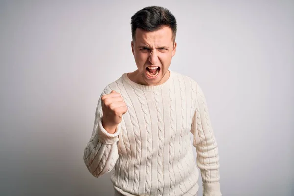 怒りで叫んでいる間 白の隔離された背景にカジュアルな冬のセーターを身に着けている若いハンサムな白人の男は怒って怒って拳を上げ 激怒しました 激怒と積極的な概念 — ストック写真