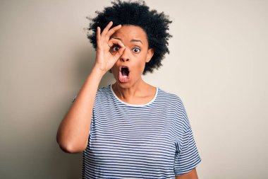 Kıvırcık saçlı, çizgili tişört giyen, şaşırmış yüzüyle şaşırmış, parmaklarından bakan güzel Afro-Amerikan bir kadın. İnançsız ifade.