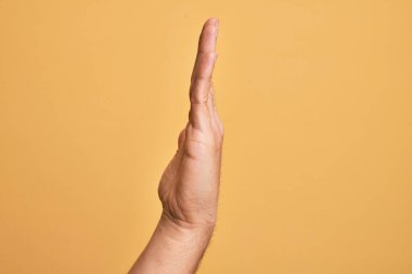 Kafkasyalı bir gencin eli, sarı arka planda parmaklarını gösteriyor. Uzanmış el hareketlerini gösteriyor, itiyor ve duruyor.