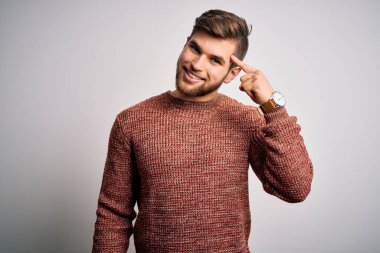 Sakallı ve mavi gözlü genç bir adam beyaz arka planda sıradan bir süveter giyiyor. Tek parmakla kafasını göstererek gülümsüyor. Harika bir fikir ya da düşünce, iyi bir hafıza.
