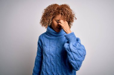 Beyaz arka plan üzerine balıkçı yaka kazak giyen güzel Afro-Amerikan kadın yorgun burnu ve gözleri ovuşturarak yorgunluk ve baş ağrısı hissediyor. Stres ve hüsran kavramı.