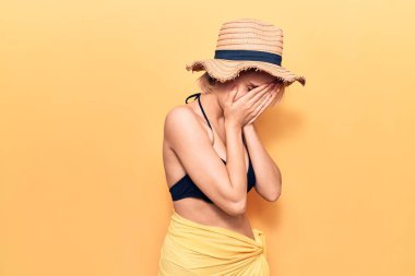 Bikini giyen güzel sarışın kadın ve ağlarken yüzünü ellerle kapatan üzgün yüzlü yaz şapkası takıyor. depresyon kavramı. 