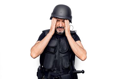 Kurşungeçirmez yelek giyen orta yaşlı yakışıklı bir polis ve kafasında el olan güvenlik kaskı var. Stres yüzünden baş ağrısı çekiyor. Migren ağrısı..