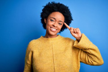 Kıvırcık saçlı, sarı kazaklı, güzel Afro-Amerikan bir kadın. Tek parmağıyla gülümseyerek, harika bir fikir ya da düşünceyle, iyi bir hafızaya sahip.