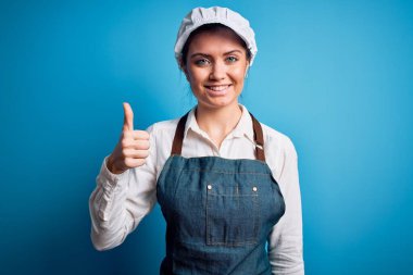 Mavi gözlü, mavi önlüklü ve mavi arka planda şapkalı genç, güzel fırıncı kadın mutlu bir el hareketi yapıyor. Kameraya bakıp başarıyı gösteren ifade onaylanıyor.