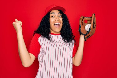 Genç Afro-Amerikan kıvırcık kadın beyzbol şapkası takıp beyzbol oynuyor. Top ve eldiven kullanıyor. Gururla bağırıyor, zaferi kutluyor ve başarıyı kutluyor.
