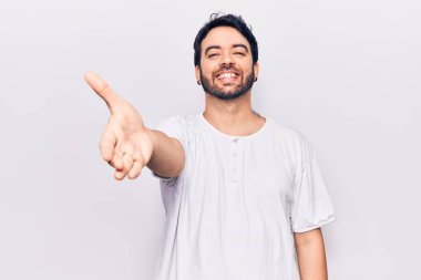 Gündelik kıyafetler giyen genç İspanyol adam dostça bir selamlama ve hoş geldin hediyesi olarak el sıkışmayı sunuyor. başarılı iş. 