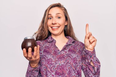 Arjantin 'in geleneksel içkisini içen genç, güzel sarışın kadın bir fikir veya soruyla gülümsüyor ve mutlu bir yüzle işaret ediyor. 