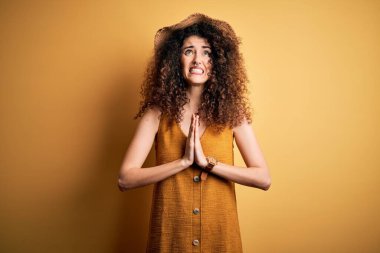 Güzel esmer kadın tatilde, kıvırcık saçlı, piercingli, şapkalı, elbiseli, dilenci ve dua eden elleri olan yüzünde umut ifadesi olan çok duygusal ve endişeli bir kadın. Yalvarıyorum..