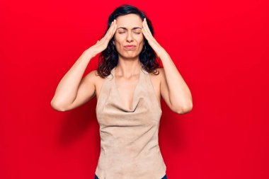 Genç, güzel, İspanyol bir kadın. Elleri başının üstünde, günlük kıyafetler giyiyor. Stres yüzünden baş ağrısı çekiyor. migren ağrısı. 