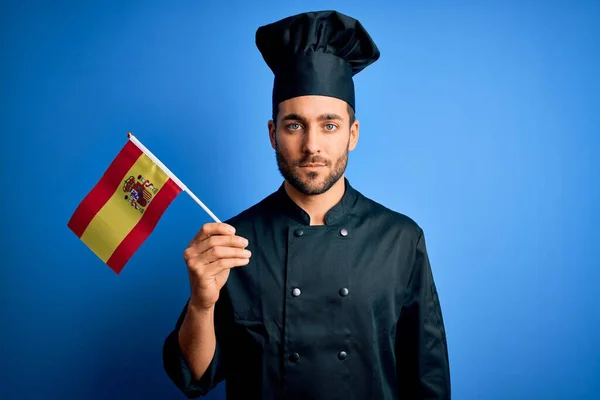 Mladý Pohledný Kuchař Muž Plnovousem Uniformě Drží Španělskou Vlajku Sebevědomým — Stock fotografie
